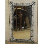 A decorative wall mirror rectangular with etched borders set within decorative iron framed