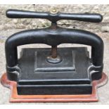 A vintage cast iron book press with central screw thread and mounted on a shaped timber board 34