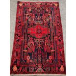 A Nahawand carpet brightly coloured with a central medallion surrounded by stylised flowers on a