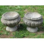 A pair of weathered cast composition stone garden urns, the circular lobed bowls with flared rims