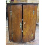 Georgian fruitwood hanging corner cupboard of bow fronted outline, with painted interior with