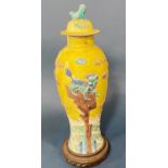 Chinese sancai baluster vase with cover, four-character mark underneath, on carved wooden stand,