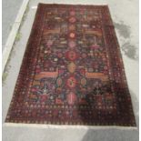 A Middle Eastern rug decorated with stylised birds and flowers on dark blue ground, 180cm x 118cm.