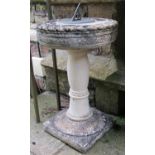 A weathered cast composition stone sundial with repeating flower head and rope twist detail