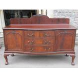 An Edwardian mahogany dining room set, the sideboard of serpentine form enclosing an arrangement