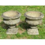 A pair of weathered cast composition stone garden urns, the circular lobed bowls with flared rims