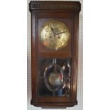 A 1930s oak wall clock with anodised dial, the lower part of the case with glazed panels enclosing