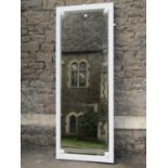 A wall mounted dressing mirror the painted frame enclosing a bevelled edge mirror plate with applied