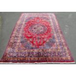 A good quality large Meshed carpet with central floral medallion on a red ground interspersed with