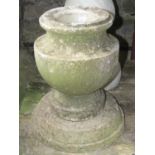 A small weathered marble urn raised on an associated stepped circular composite base together with a