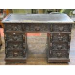 Victorian oak pedestal writing desk in the gothic revival manner, fitted with nine frieze drawers