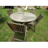 A weathered hardwood circular topped garden table with slatted panels raised on x framed folding