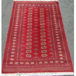 A Turkoman carpet with alternating rows of gul a central panel on a red ground,190cm x 130cm approx