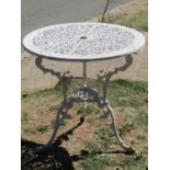 A cream painted cast aluminium garden terrace table of circular form, with decorative pierced