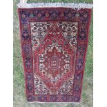 A small Middle Eastern rug with a central medallion surrounded by stylised flowers, 130cm x 77cm