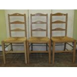 A Harlequin set of three pale oak ladderback chairs, almost certainly Heals, with rush seats n