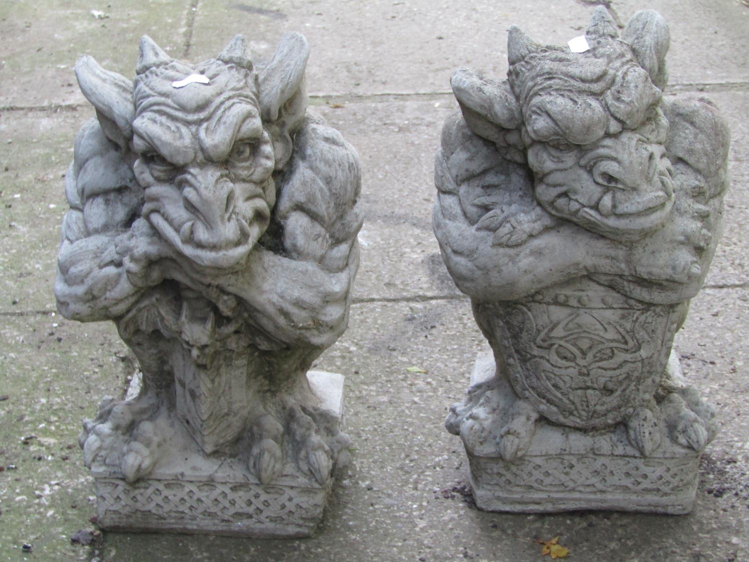 Two similar composition stone gargoyle ornaments with shield and celtic knot detail, 38 cm high