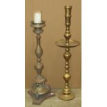 An outsized brass candlestick with wide drip pan, 105cm high, together with a further Gothic style