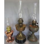 An Aladdin brass oil lamp with chimney but no shade, two further oil lamps with chimneys but no