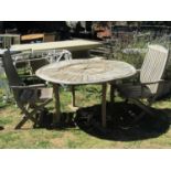 A Firman weathered hardwood garden table with circular radiating slatted top, raised on square cut