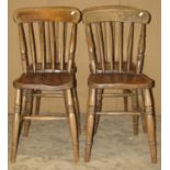 A set of four Windsor stained elm and beechwood stick back kitchen chairs raised on ring turned