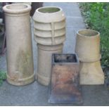 Four weathered buff coloured clay chimney pots of varying size and design to include a canon
