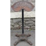 A vintage novel cast iron bar stool with tractor seat, raised on a tubular support and swept paw