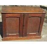 A small oak table top cabinet enclosed by a pair of rectangular chamfered panelled doors, the