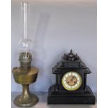 A Victorian black slate mantel clock of classical design, together with an oil lamp with twin