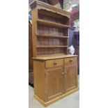 A stripped and waxed pine cottage kitchen dresser, the base enclosed by a pair of rectangular