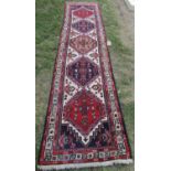 A Malayer runner with diamond shaped medallions with geometric patterns in blues and reds, 297cm x