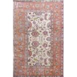 A pale Persian carpet with scrolled floral sprays running orange borders upon an ivory ground, 300cm