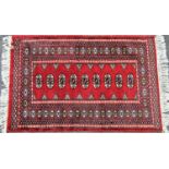 A small Turkoman rug with nine elephant foot gul in a central panel on a red ground,120cm x 80cm