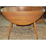 An Ercol elm and beechwood dining table raised on splayed square tapered supports together with a