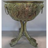 A brass punch bowl with lion rampant coat of arms and lion mask handles, raised on three dolphins,