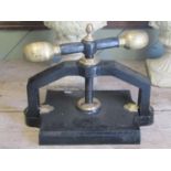 An antique cast iron book press with central screw thread, club handle, acorn finial, brass/possibly