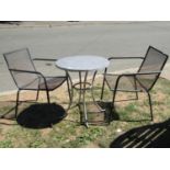 A small contemporary garden table with circular radiating mosaic patterned top, raised on swept