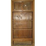 A slender pine freestanding bookcase partially enclosed by a pair of glazed panelled doors, over