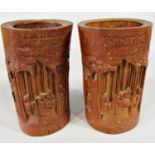 A pair of carved bamboo brush pots showing characters in a landscape, 19cm tall approx