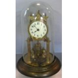 A brass anniversary clock with turned column supports beneath a glass dome