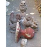 A weathered cast composition stone garden ornament in the form of a seated owl raised on an