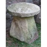 A weathered natural stone staddlestone of tapered form beneath a domed cap, 55cm diameter x 60cm