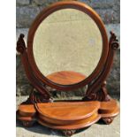 A Victorian mahogany toilet mirror of oval form with scrolled acanthus supports set on a bow fronted