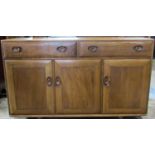 An Ercol elm low sideboard enclosed by three rectangular doors beneath two frieze drawers with