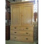 A 19th century stripped pine linen cupboard in two sections, the upper enclosed by a pair of