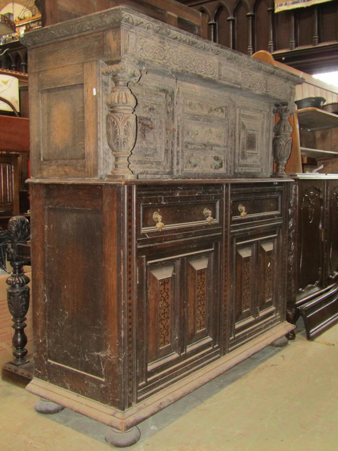 An antique old English style oak court cupboard enclosed by an arrangement of cupboards and