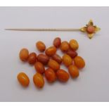 Yellow metal floral stick pin set with coral, 3.7g, together with a quantity of loose amber coloured