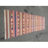A large flat weave Dhurrie carpet with repeating multi coloured horizontal stripe, 470cm x 160cm