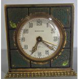 An art deco travelling clock in a brass case, the panelled case engraved with fish and weed, the