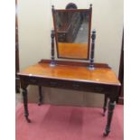 A Victorian mahogany dressing table on turned supports, the rectangular mirror with further turned